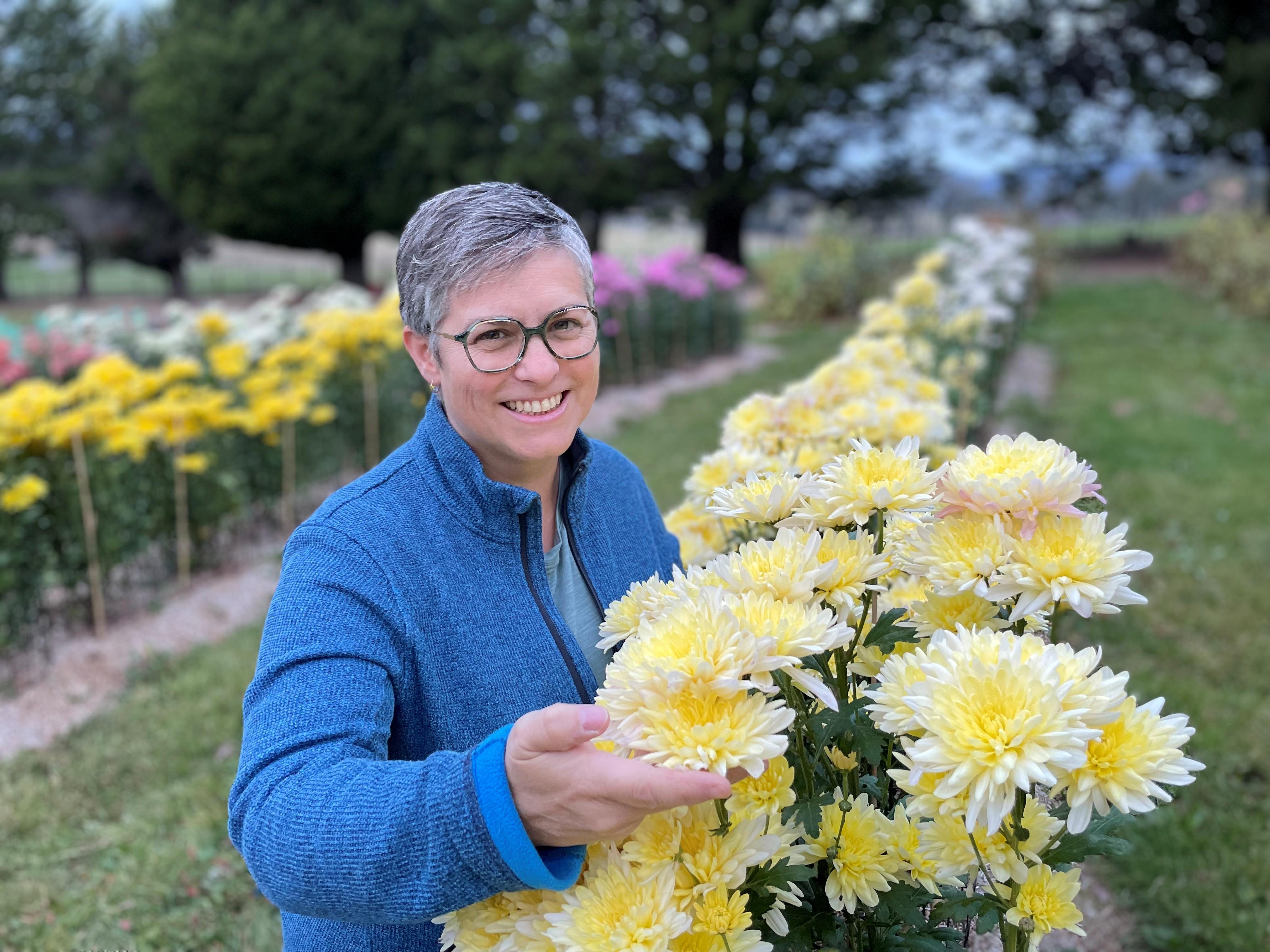Donna Tracey with the  chrysanthemums that flourish on the  couple’s property.