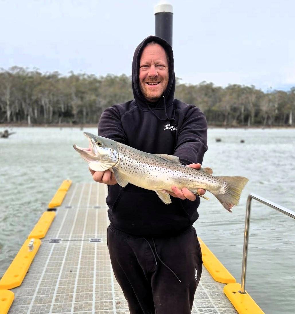 Justin Stevens with a solid male brown trout he caught spinning off the jetty at Lake Leake last weekend.