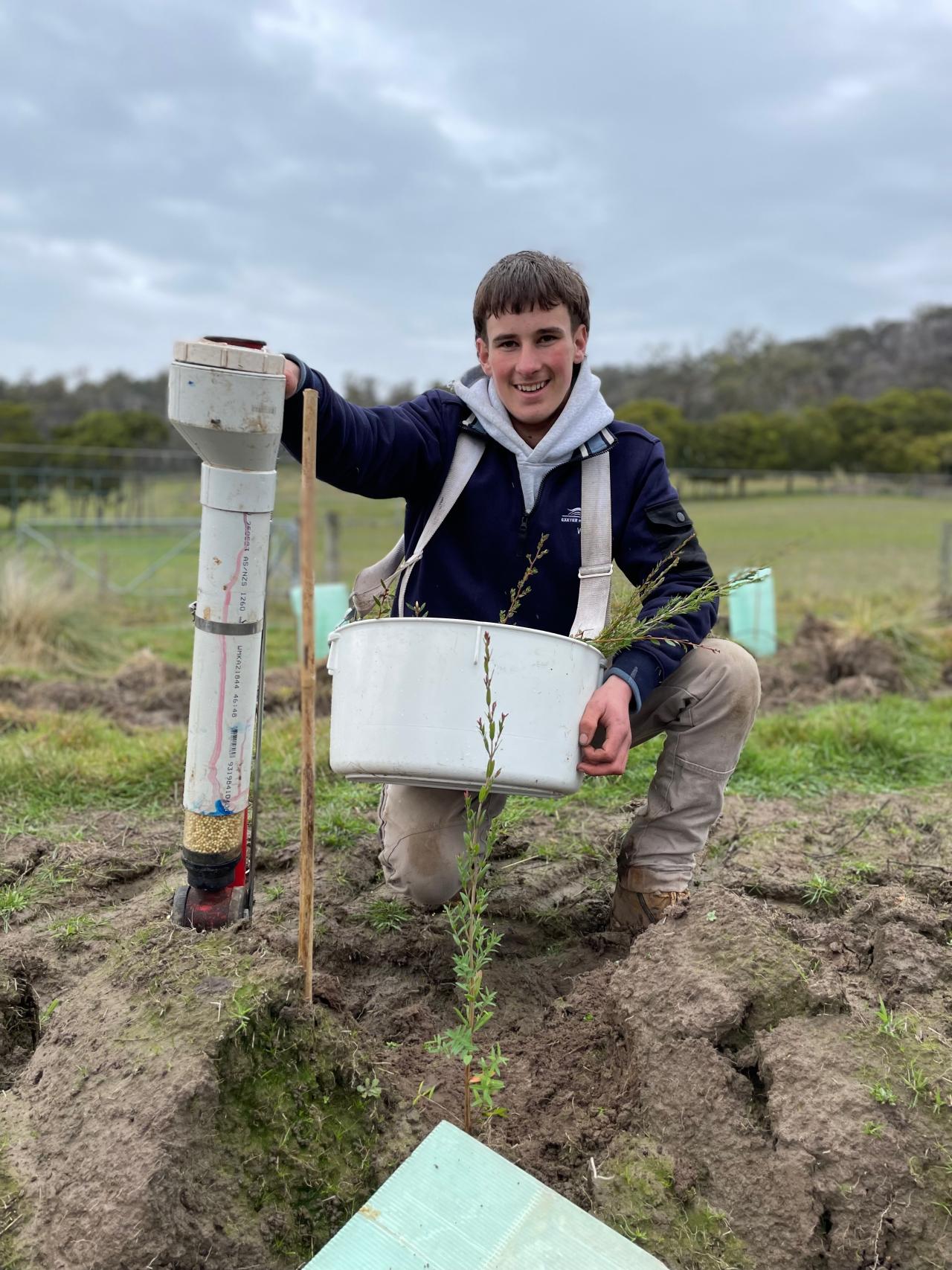 Exeter High School student Will Gangell of Westbury planting trees on the school farm.